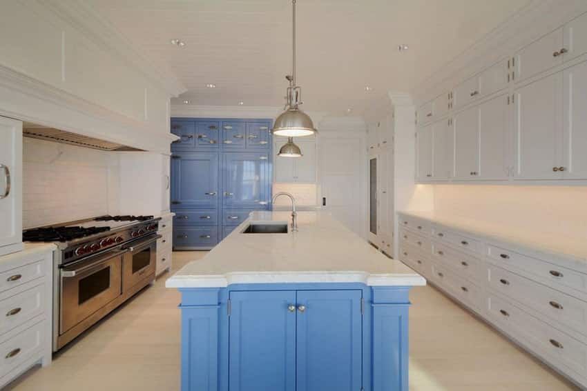 Luxury kitchen with blue and white cabinets island with carrara marble counter and subway tile backsplash