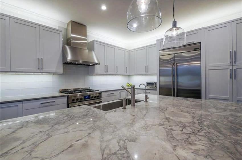 Luxury kitchen with calacatta carrara marble counter gray cabinets and white backsplash