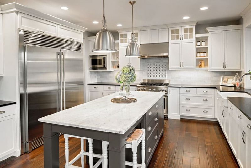 luxury white cabinet kitchen with gray island black counter and wood floors 800x534