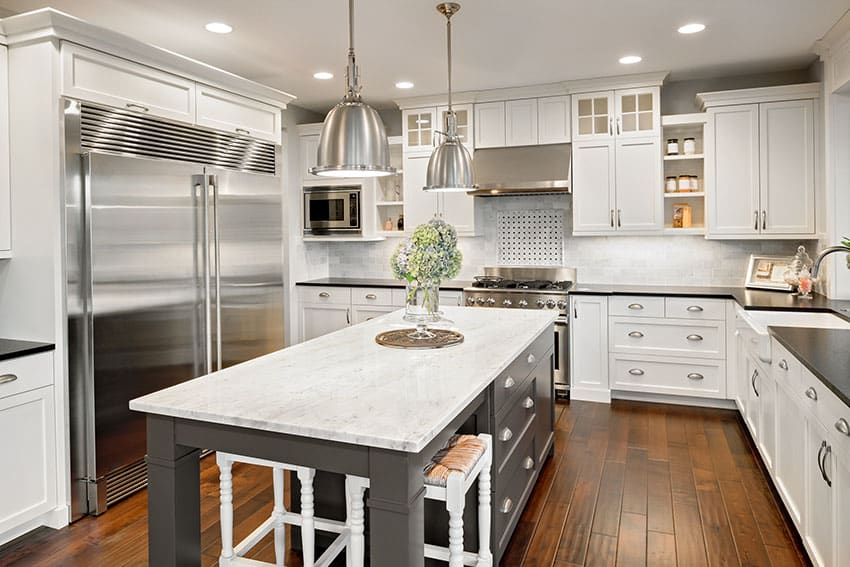 Luxury white cabinet kitchen with gray island black counter and wood floors