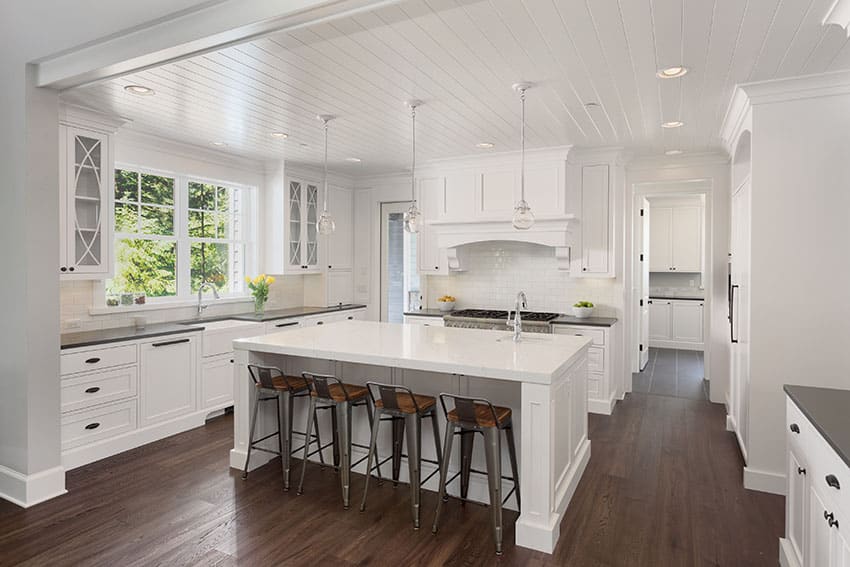 Luxury kitchen with shaker cabinets, marble countertops, pendant lighting, and custom range hood