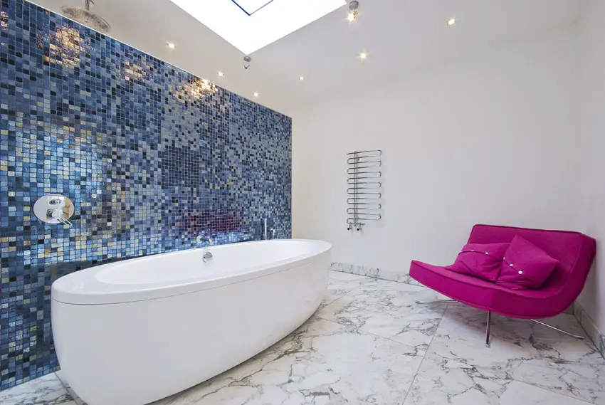 Bathroom with mosaic tiled wall, fuschia chair and skylight