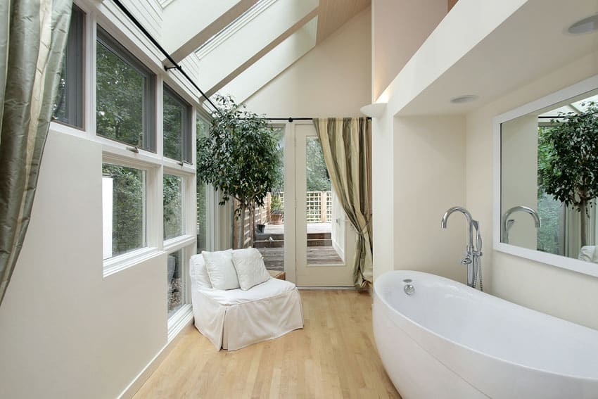 Modern bathroom with wood floors, large windows and lounge chair