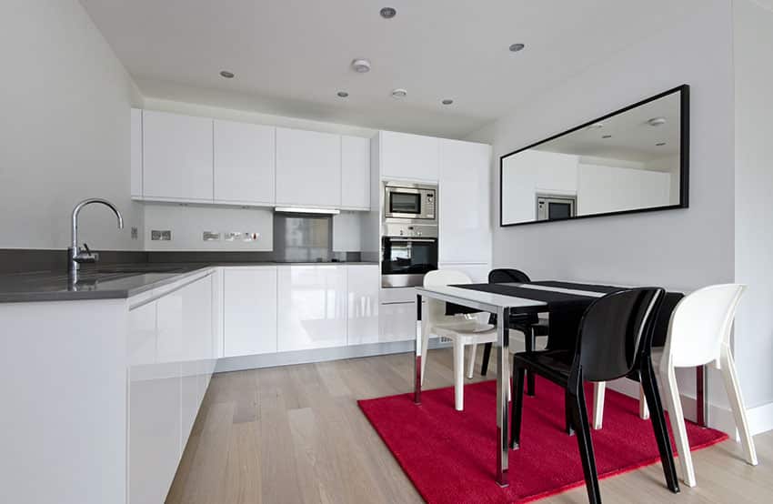 Kitchen with red rug, black and white chairs and mirror with black frame