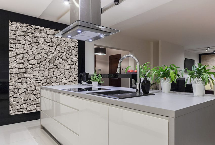 Kitchen with stacked stone wall, black metal basin and countertop stove
