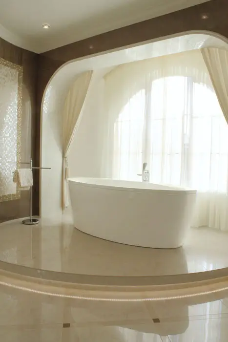 Modern minimalist bathroom with bathtub on elevated patform and large window 