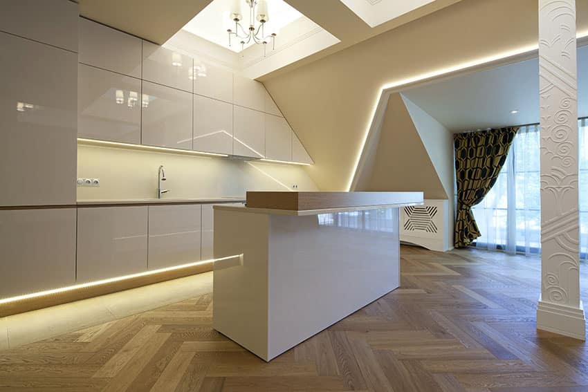 Kitchen with herringbone pattern flooring, quartz counters with glossy base and strip lighting
