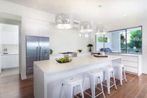 Modern White Cabinet Kitchen With Island With Simple Bar Stools And Silver Drum Pendant Lights 300x200 