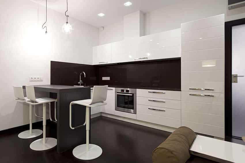 Modern white kitchen with small breakfast bar peninsula and brown glass backsplash