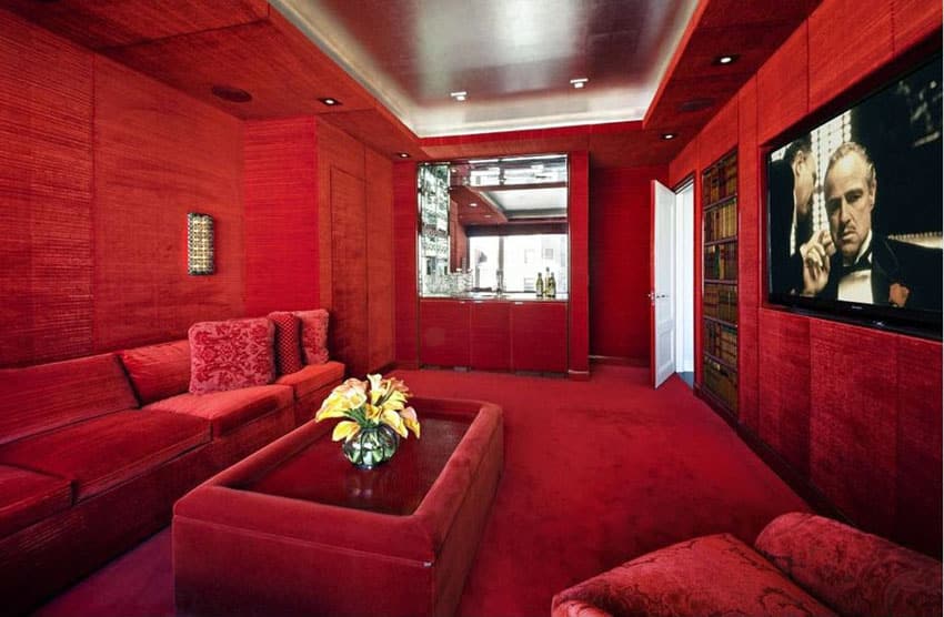 Plush red velvet movie room with wide screen television and home bar