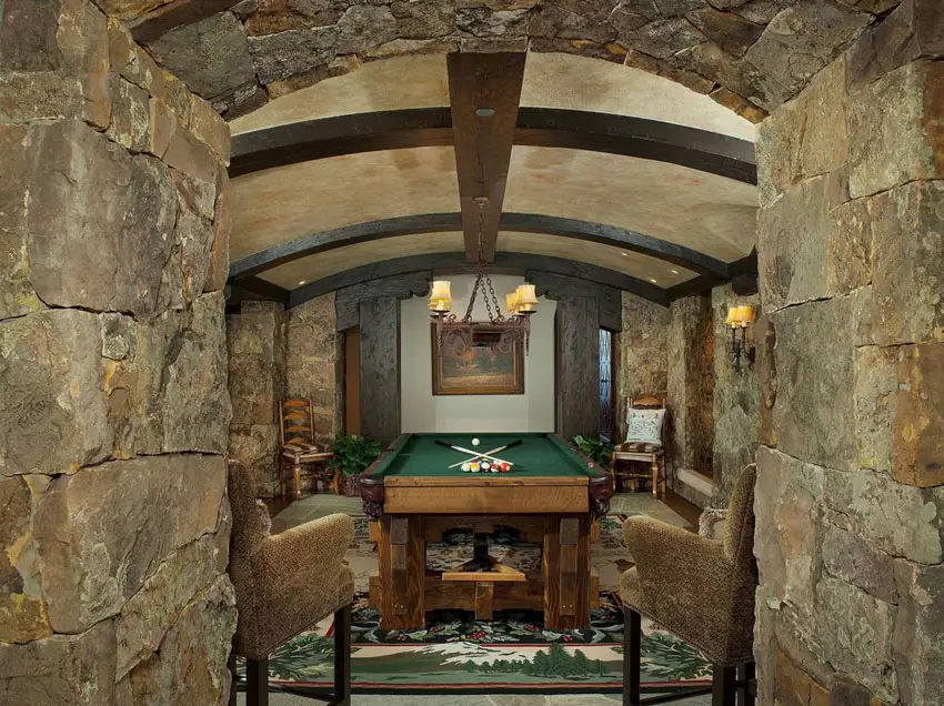 Rustic cave room with stone arched ceiling and billiards table