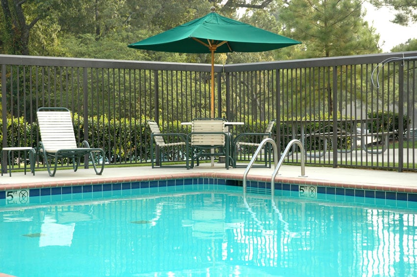 Peaceful poolside scene, with umbrella, table and chairs