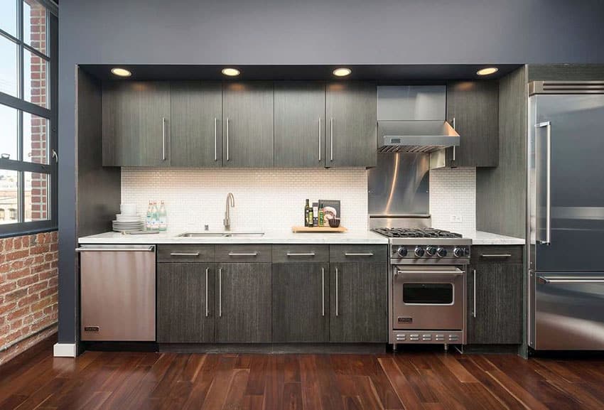 Kitchen with brick wall, gray cabinetry and recessed overhead lighting