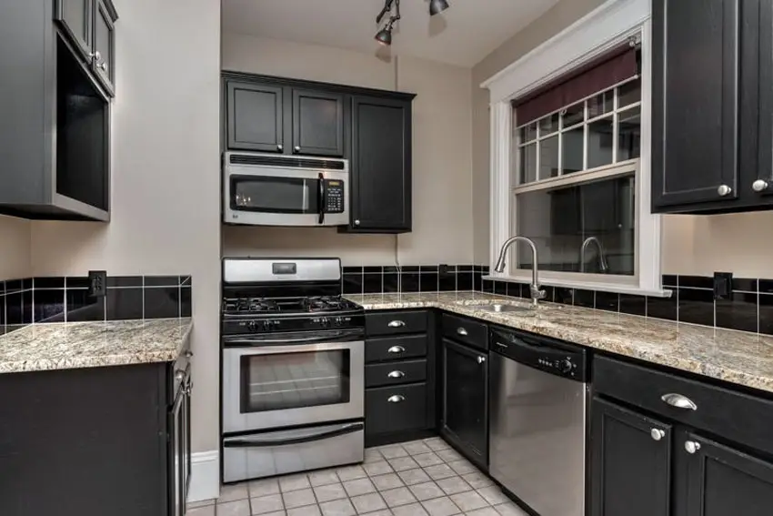 Small galley kitchen with black cabinets and avalon white granite