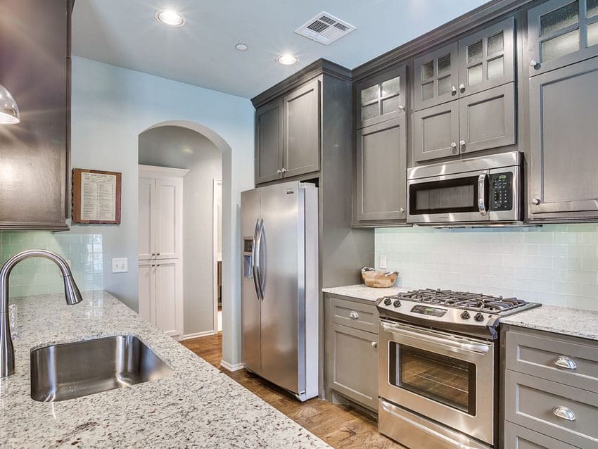 Kitchen with blue walls with gray cabinets, andino white granite and steel sink
