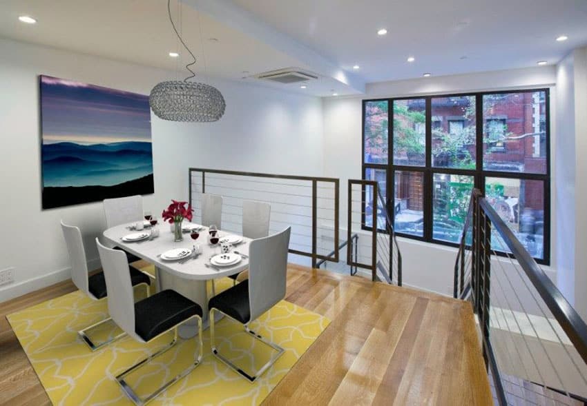 Dining table on the mezzanine floor, black window frames and blue wall art