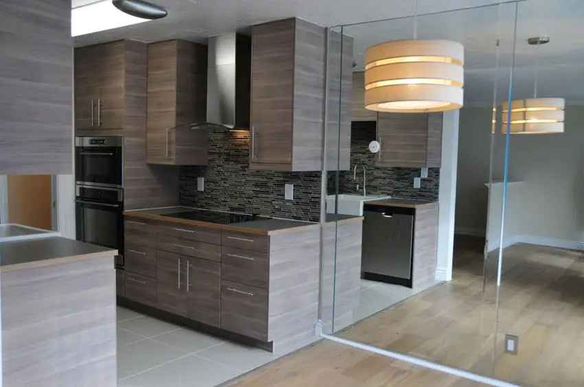 Small modern galley kitchen with brown textured laminate cabinets and gray porcelain tile floors