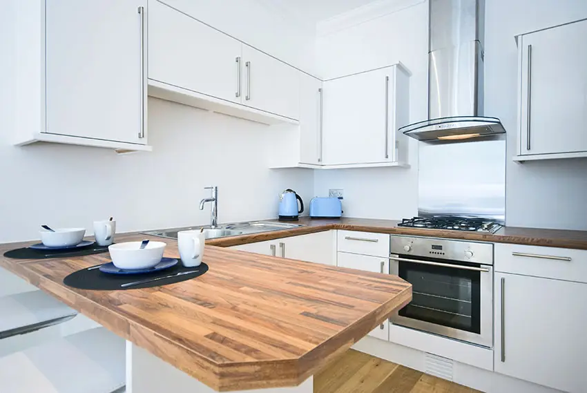 Small white modern kitchen with wood counter peninsula