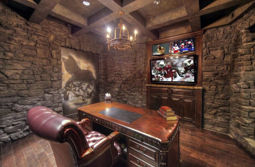 Stone wall man cave office with desk, wood flooring and big screen television