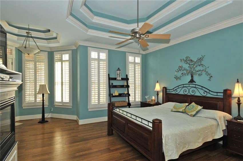Traditional bedroom with teal painted walls, wood flooring and white molding