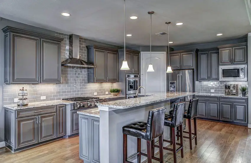 Traditional kitchen with gray cabinets and subway tile backsplash with white granite countertop and breakfast bar island