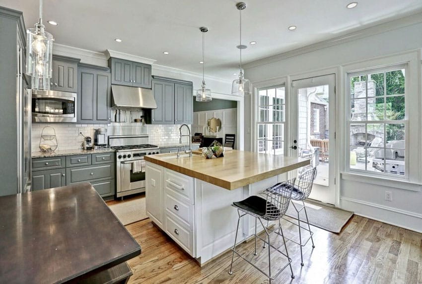 Traditional kitchen with gray cabinets, white island, white subway tile and wood countertops