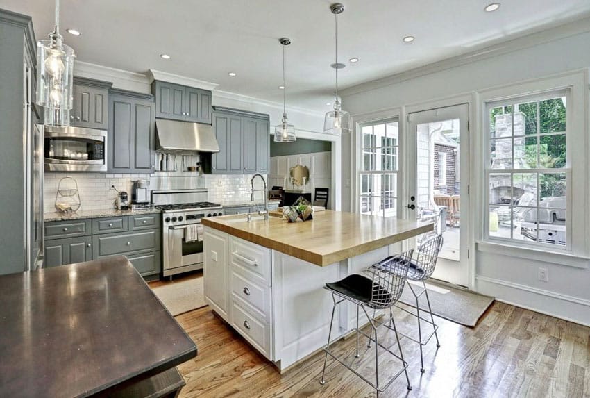 Kitchen with grey cabinets, butcher's block countertop and wrought iron chairs