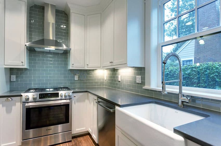 Kitchen with glass tiles for the walls, white farmer sink and soapstone countertops