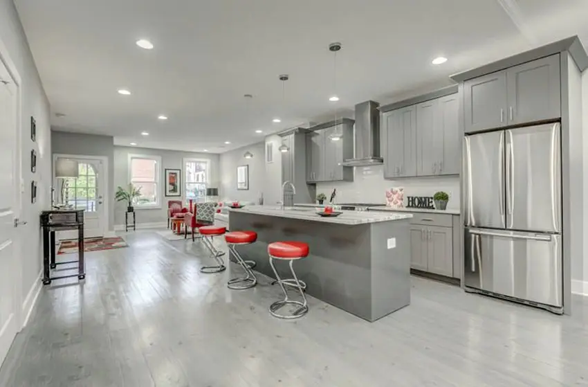 Transitional kitchen with gray cabinets and white marble countertops with breakfast bar island
