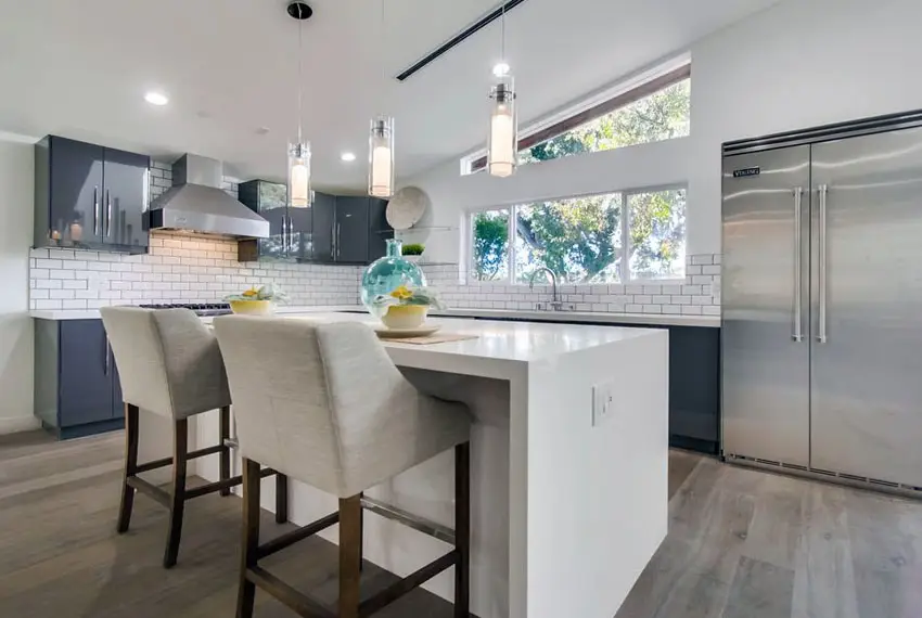 Transitional kitchen with gray cabinets, white counter and subway tile