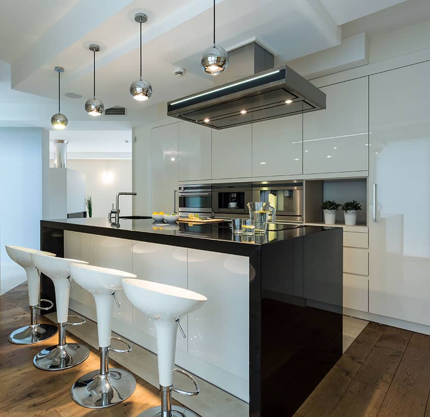 Ultra modern white kitchen with round metal pendant lights and black counter island