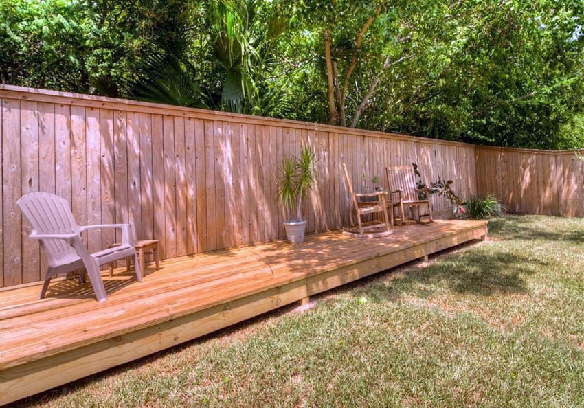 Vertical wood fence with raised deck in backyard
