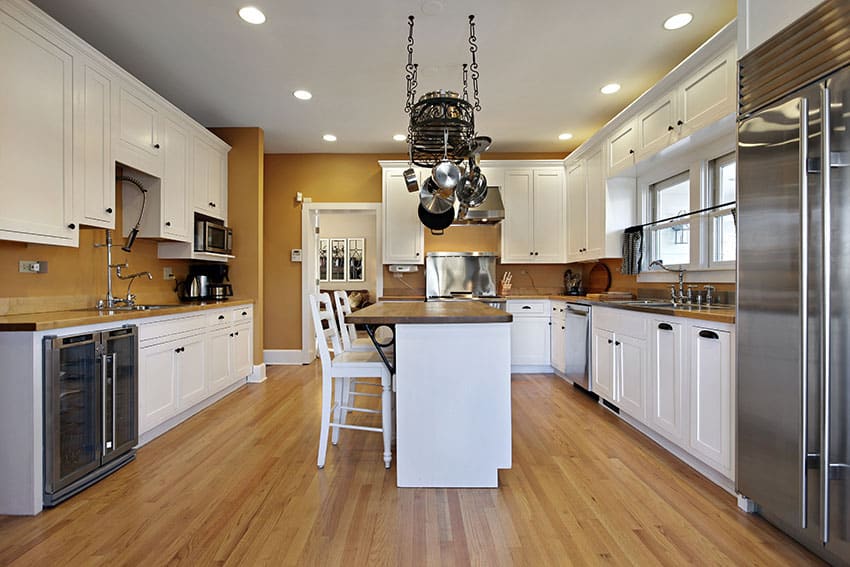 Kitchen with hanging pots and pans, small breakfast bar island and wood flooring