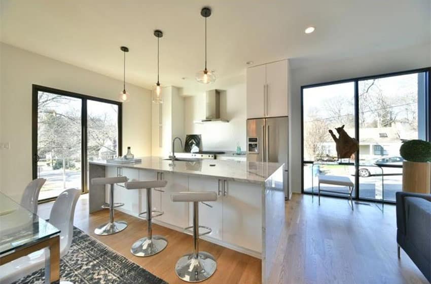 White modern kitchen with breakfast bar, chrome adjustable bar stools and round pendant lights