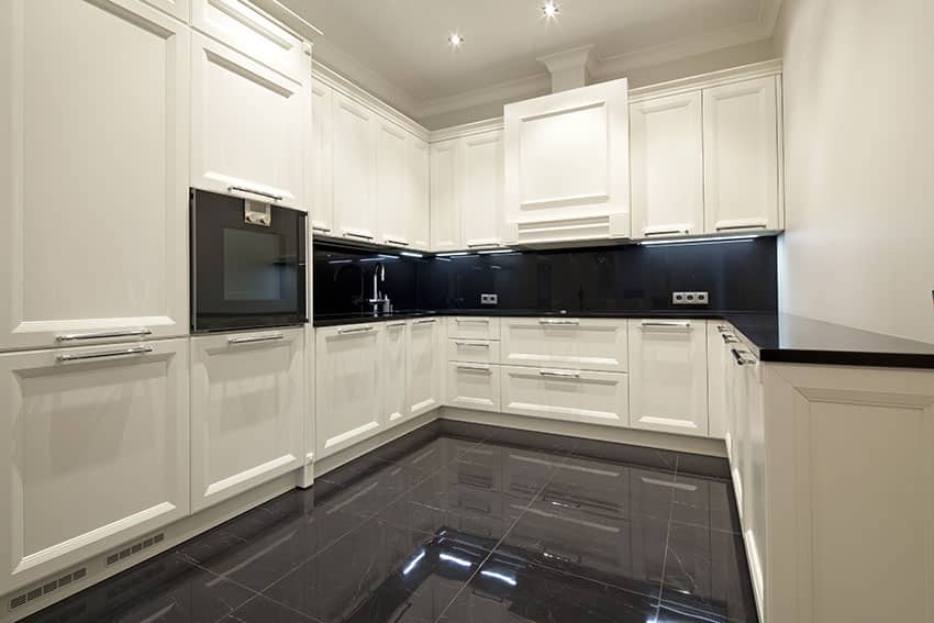 U shaped kitchen with black tiles, raised paneled cabinets and black backsplash