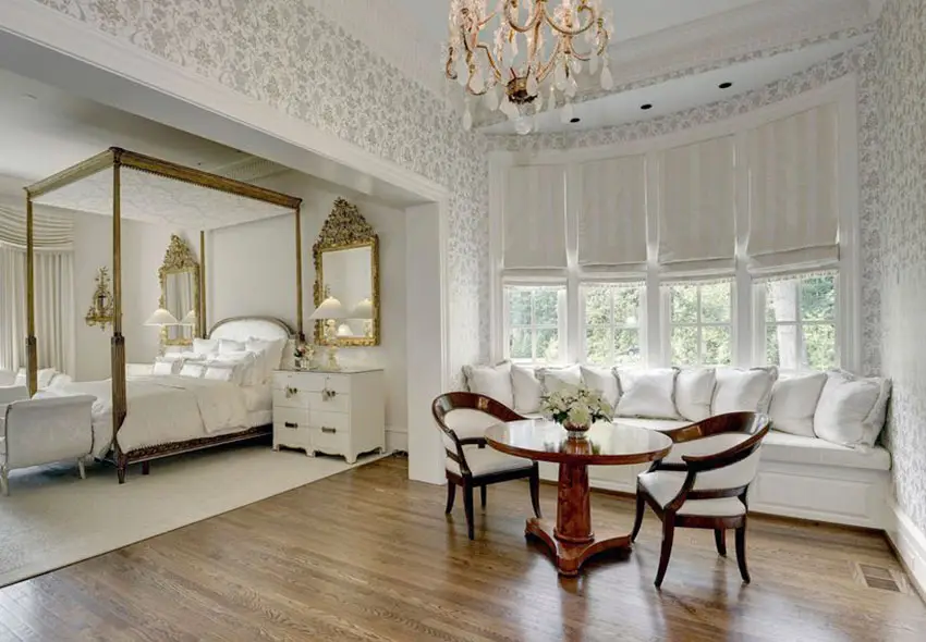 Four poster bed, mahogany chairs and walls with patterned wall paper