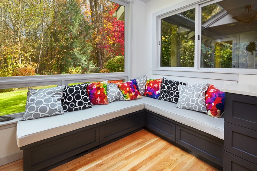 Window seat with large windows dark cabinet white cushions