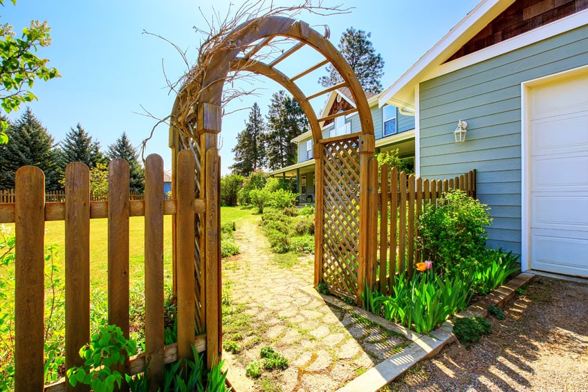 Arbor besise house with white carport door and blue siding