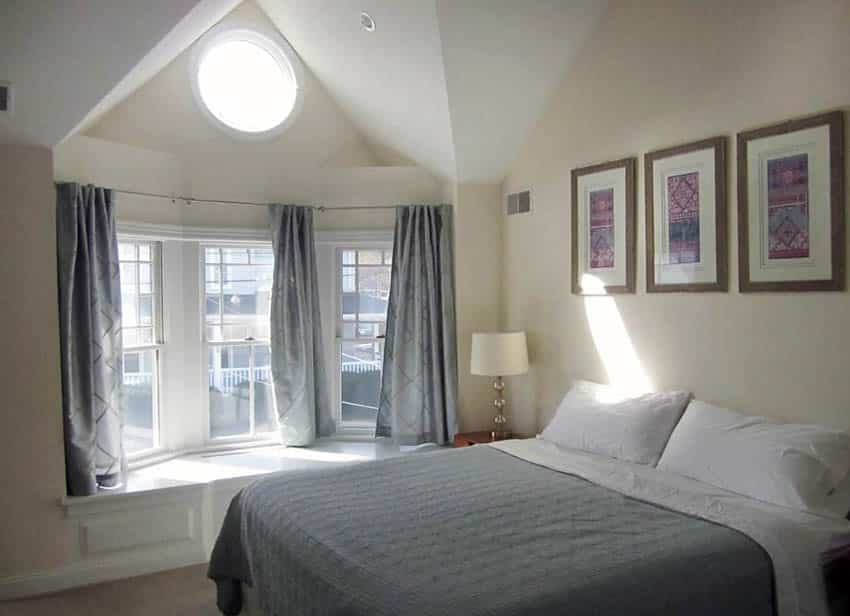 Bedroom window with grey curtains and cozy white pillows