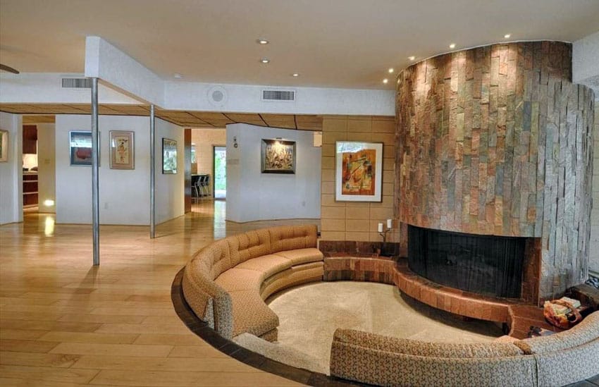 Curved modern sunken living room with circular slate fireplace and hickory wood floors