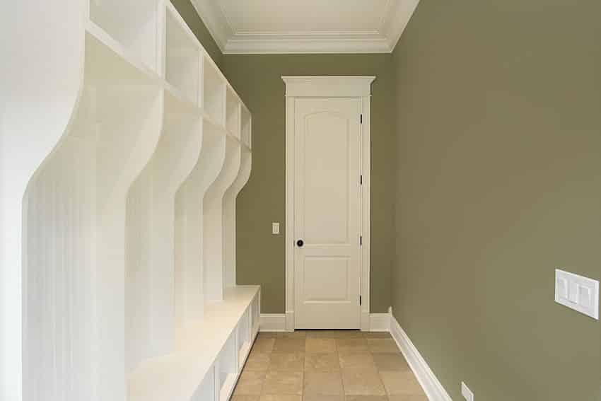 Mudroom with white casework, beige square tiles and walls in calke green