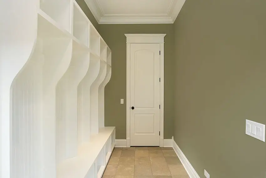 Mudroom with white casework, beige square tiles and walls in calke green
