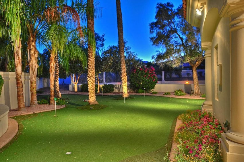 Backyard golf green with tropical plants at luxury home