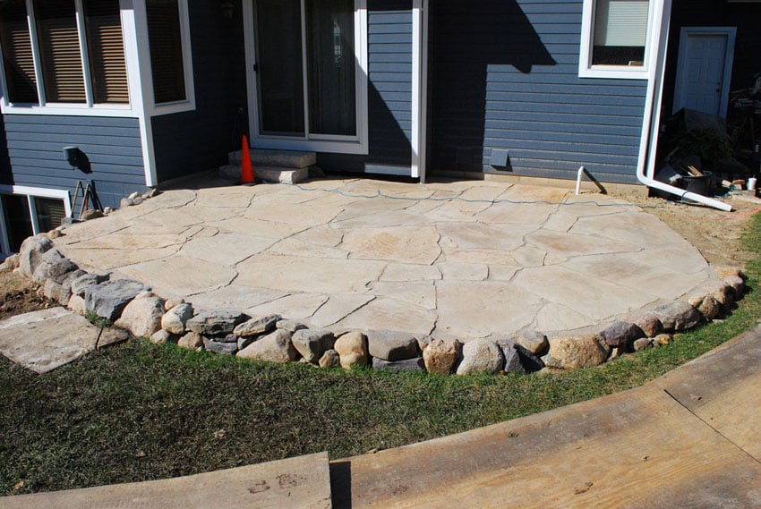 Backyard stone patio with circular design with small stone edge