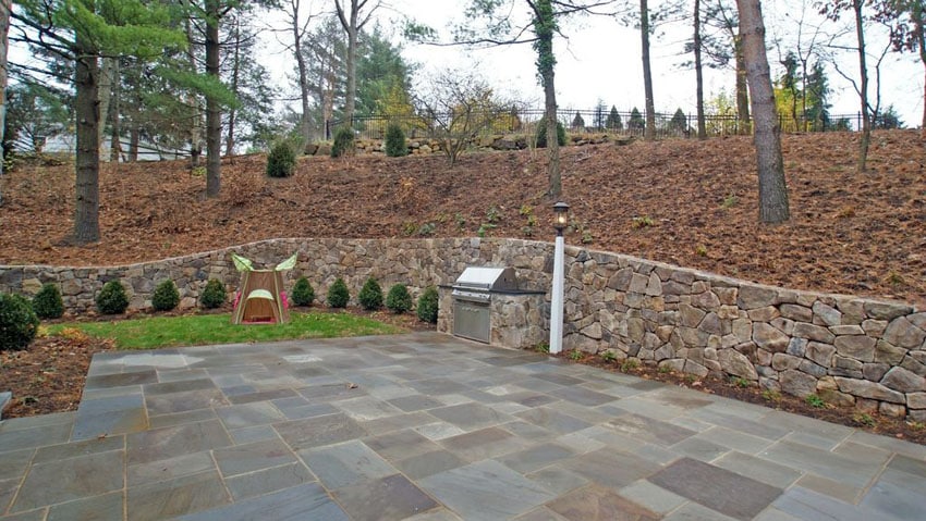 Contemporary flagstone patio with stacked stone retaining wall
