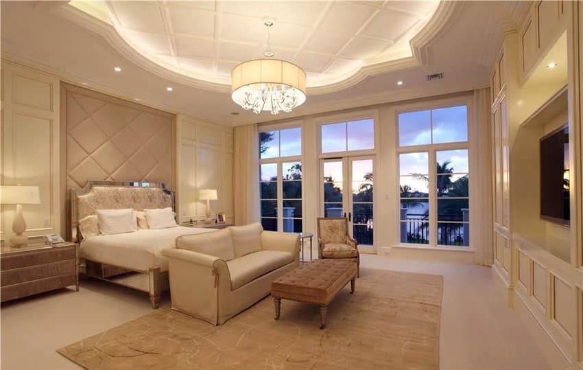 Contemporary tan bedroom with decorative tray ceiling and outdoor balcony