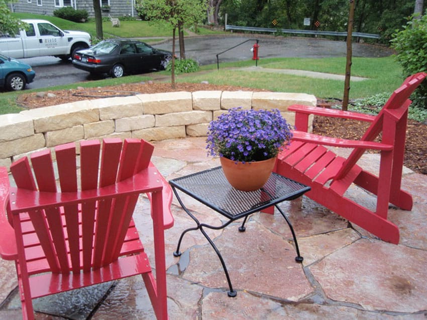 Flagstone patio with circular block wall and lounge chairs in front yard