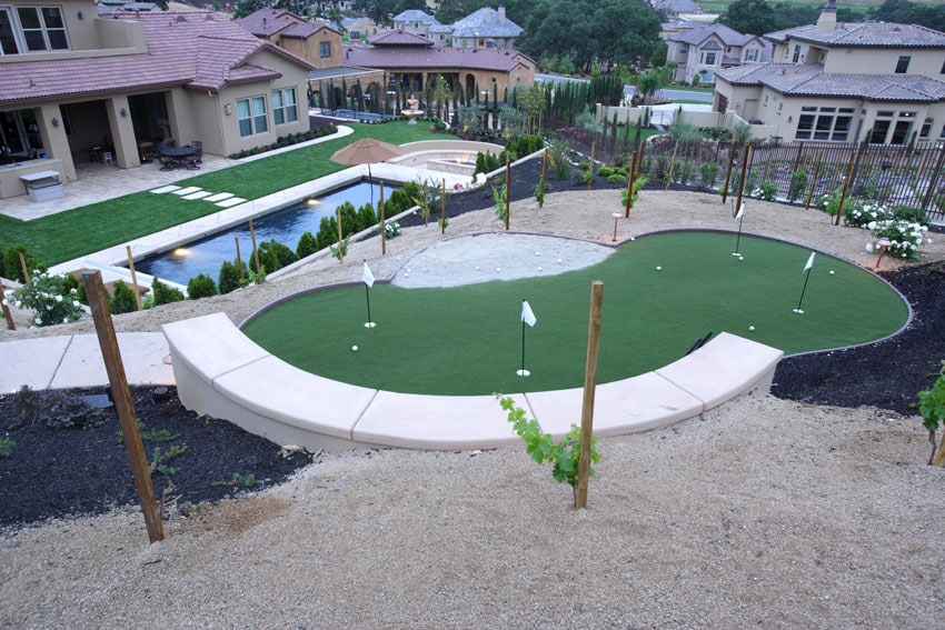 Backyard golf putting green with sandtrap and swimming pool