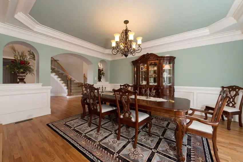 Green and white dining room with tray ceiling and wood floors