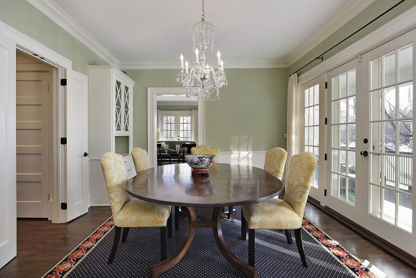 Formal dining room with green colored walls, crystal chandeliers and cream chairs